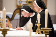 23-After professing the vows, the sister goes to the altar to sign the book on which she has written her vows.